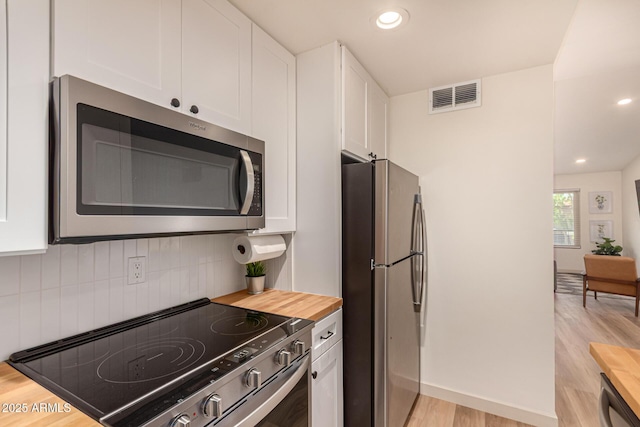 461 W Holmes Ave Unit 323, Mesa, AZ 85210 - kitchen with stainless steel appliances, wooden counters, white cabinets, light wood-style flooring, and backsplash