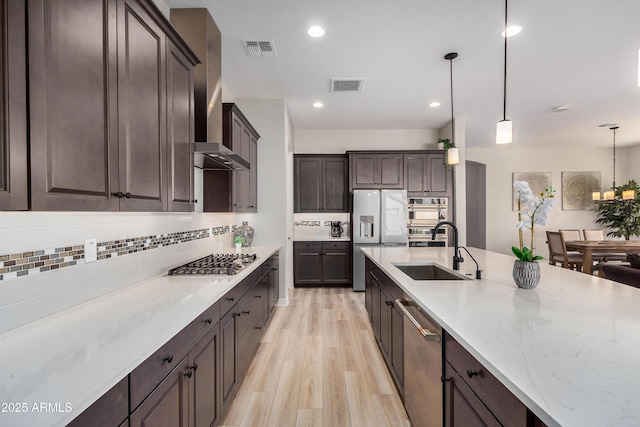 kitchen with dark brown cabinets, visible vents, appliances with stainless steel finishes, and wall chimney exhaust hood