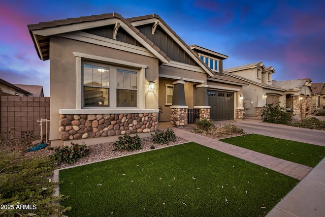 craftsman-style home with fence, driveway, a garage, stone siding, and board and batten siding