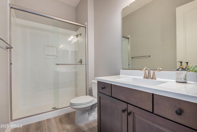 bathroom with vanity, hardwood / wood-style flooring, a shower with door, and toilet