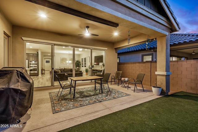 patio terrace at dusk featuring outdoor lounge area, a ceiling fan, and fence