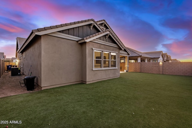 back house at dusk featuring a yard and central AC