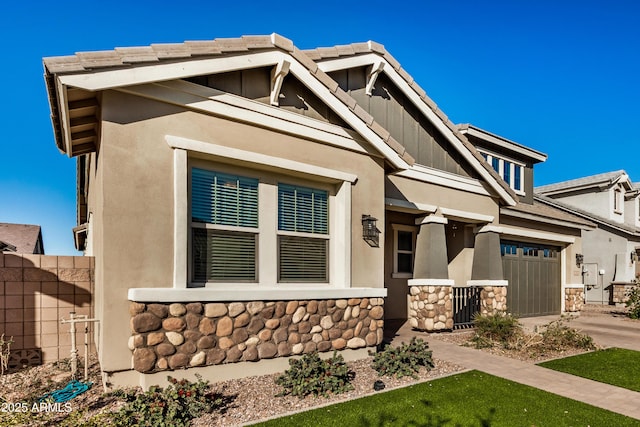 craftsman inspired home featuring fence, an attached garage, stucco siding, concrete driveway, and stone siding