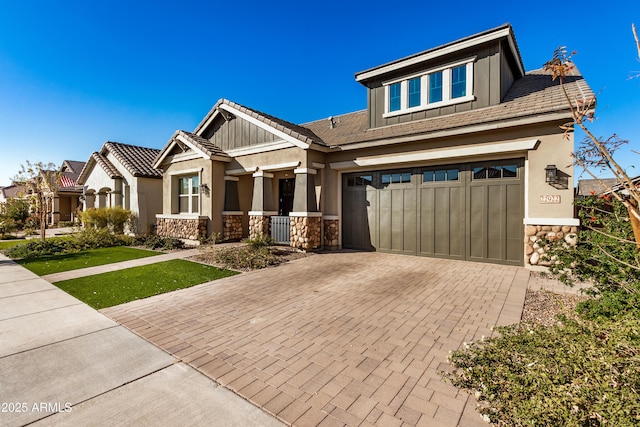 craftsman inspired home with stone siding, stucco siding, an attached garage, and decorative driveway