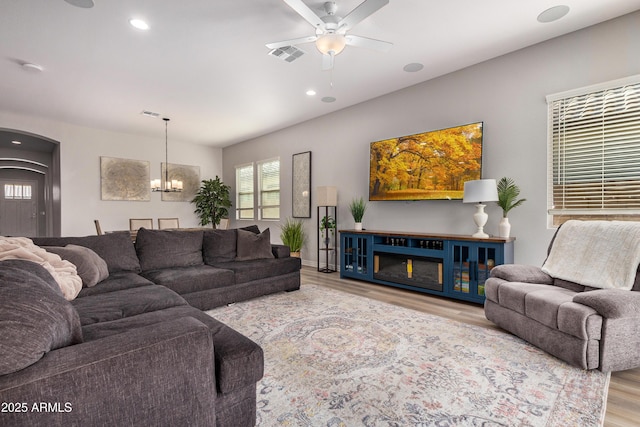 living area with visible vents, ceiling fan with notable chandelier, wood finished floors, recessed lighting, and arched walkways