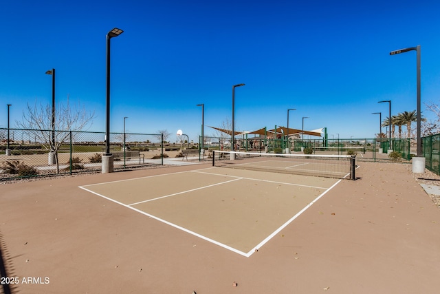 view of tennis court featuring community basketball court and fence