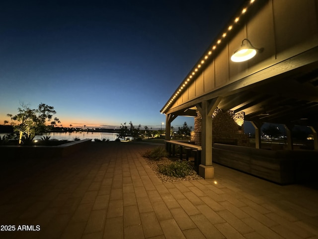 patio terrace at dusk featuring a water view