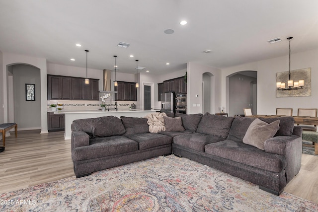 living room featuring recessed lighting, visible vents, arched walkways, and light wood-type flooring