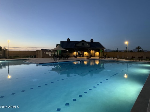 pool at dusk featuring a patio area, a community pool, and fence