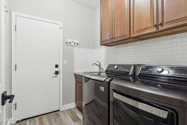 washroom featuring cabinets, light wood-type flooring, sink, and washer and clothes dryer