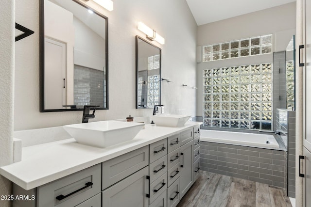 bathroom featuring hardwood / wood-style flooring, vanity, and tiled bath