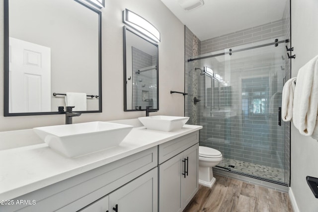 bathroom with vanity, hardwood / wood-style flooring, a shower with door, and toilet