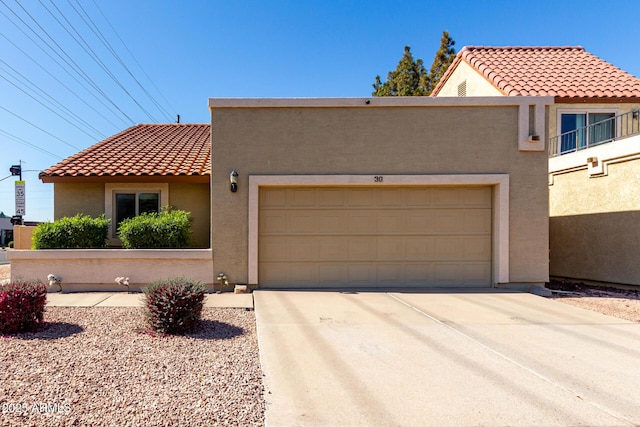 mediterranean / spanish house featuring a tiled roof, an attached garage, driveway, and stucco siding