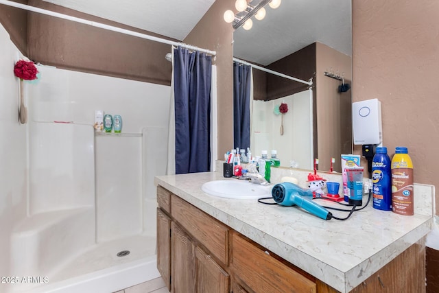 bathroom featuring a textured wall, a shower stall, and vanity