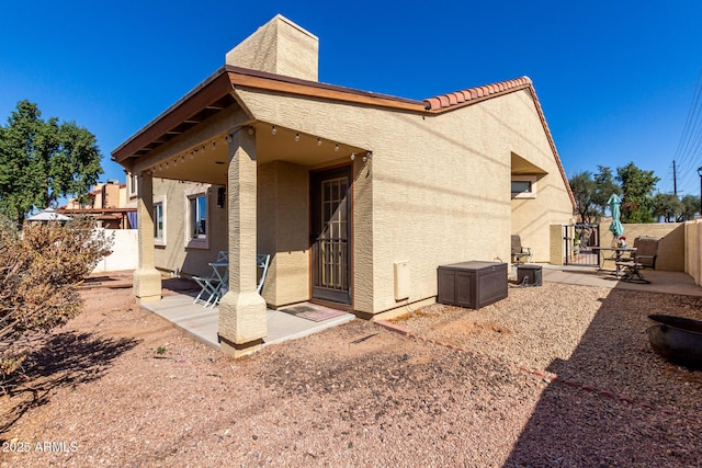 view of side of home with a patio area, fence, and stucco siding