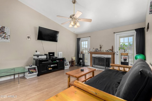 living room with vaulted ceiling, light wood-type flooring, plenty of natural light, and a tile fireplace