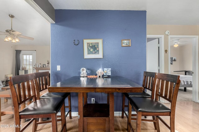 dining space featuring ceiling fan, a textured wall, and wood finished floors