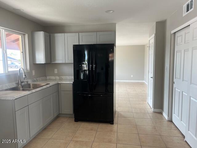 7136 W Cheryl Dr, Peoria, AZ 85345 - kitchen with a sink, black fridge with ice dispenser, light tile patterned flooring, visible vents, and light countertops
