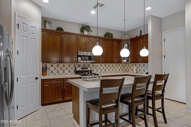 6694 S Banning St, Gilbert, AZ 85298 - kitchen with decorative backsplash, a breakfast bar area, stainless steel appliances, a center island with sink, and light countertops
