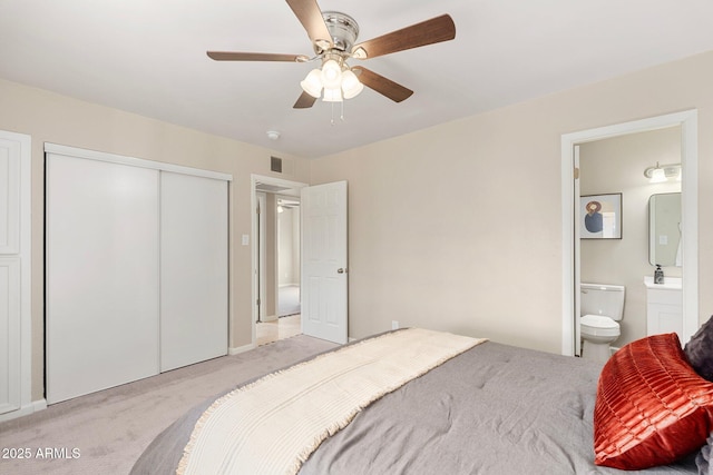 carpeted bedroom with ceiling fan, ensuite bath, and a closet