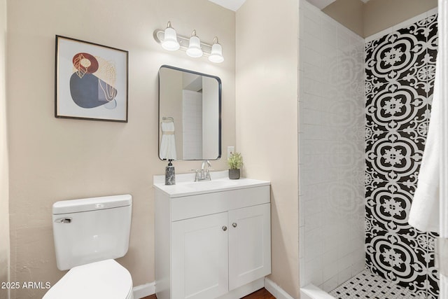 bathroom with vanity, tiled shower, and toilet