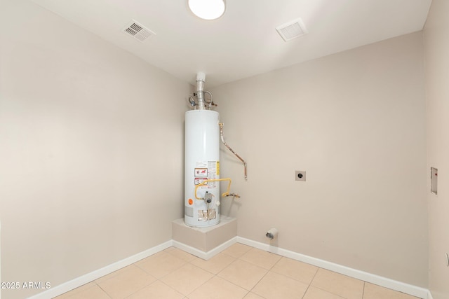 laundry area with gas water heater, electric dryer hookup, and light tile patterned floors