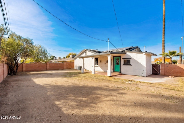 rear view of property featuring a patio area and solar panels