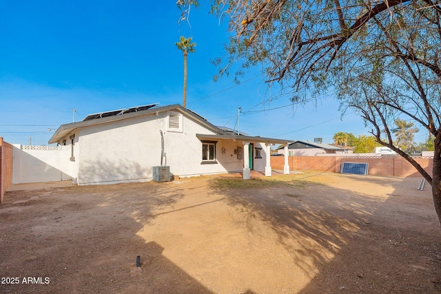 rear view of house with central AC unit and solar panels