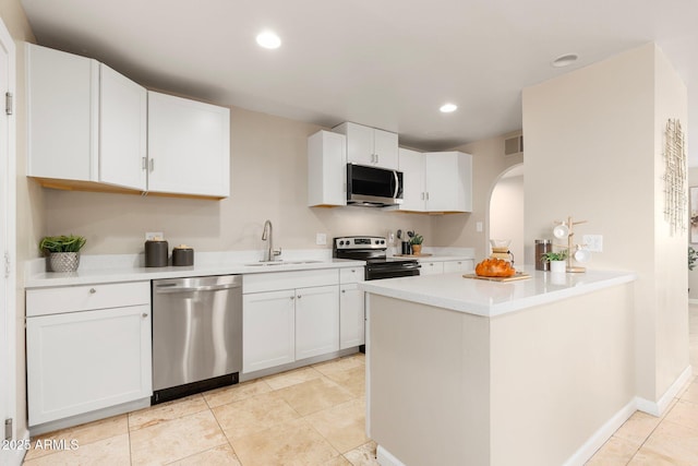 kitchen with sink, light tile patterned floors, appliances with stainless steel finishes, kitchen peninsula, and white cabinets