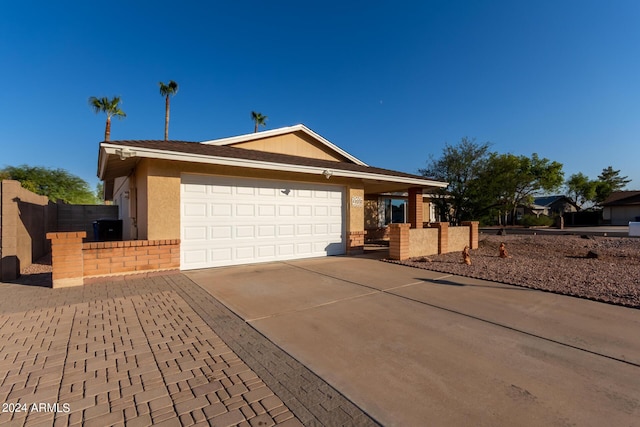 ranch-style home featuring a gate, concrete driveway, fence, an attached garage, and stucco siding