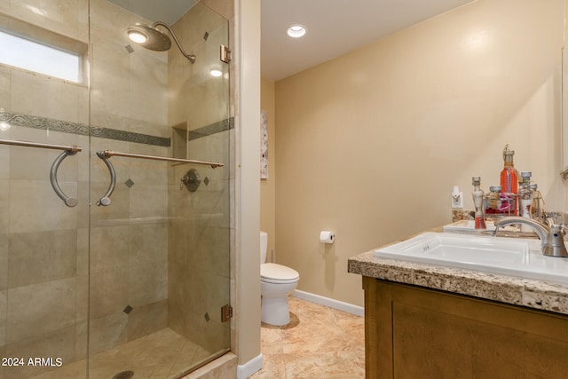 bathroom featuring vanity, a shower with shower door, and toilet