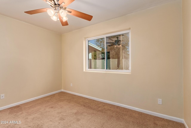 carpeted spare room featuring a ceiling fan and baseboards