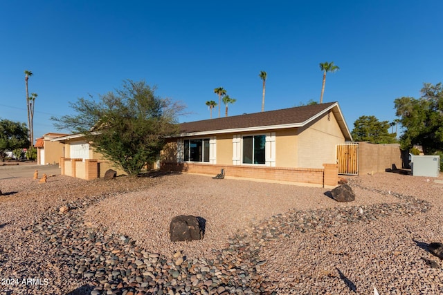 ranch-style home featuring a gate and brick siding