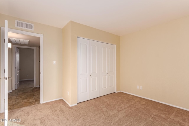 unfurnished bedroom featuring baseboards, visible vents, carpet floors, and a closet
