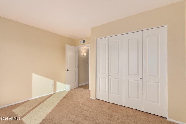 unfurnished bedroom featuring light carpet and a closet