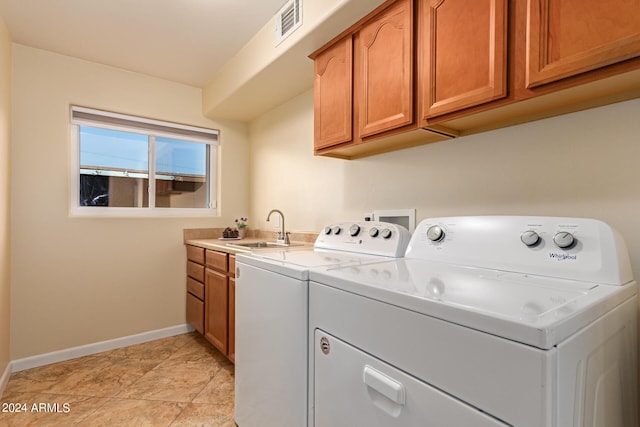 laundry area featuring visible vents, a sink, washing machine and clothes dryer, baseboards, and cabinet space