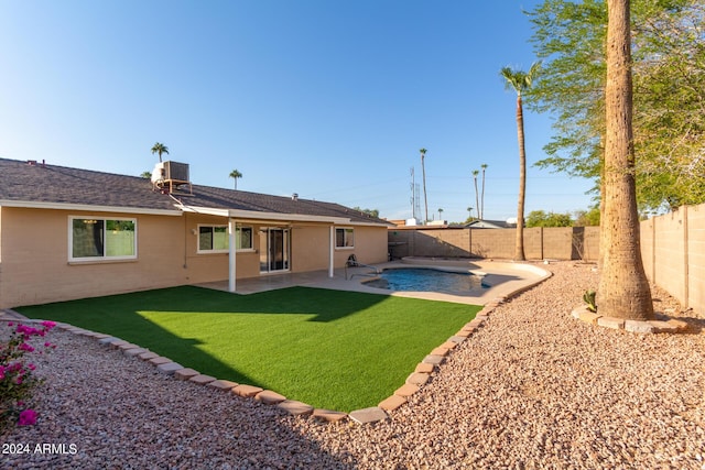 rear view of property with central AC, a lawn, a fenced backyard, a patio, and a fenced in pool