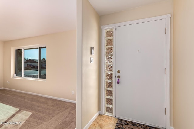 foyer entrance with baseboards and light colored carpet
