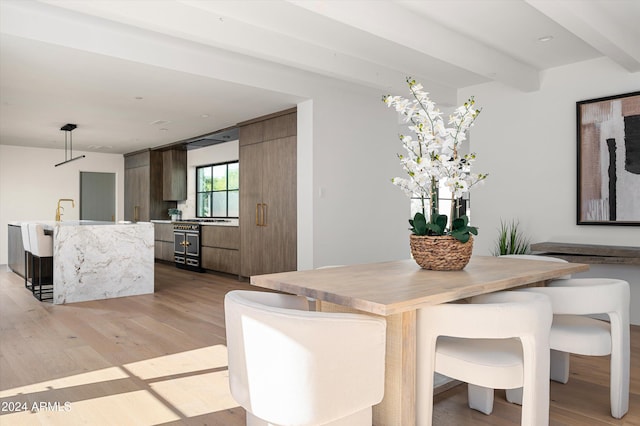 dining area featuring beamed ceiling and light hardwood / wood-style floors