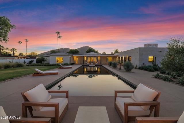 pool at dusk featuring a patio area