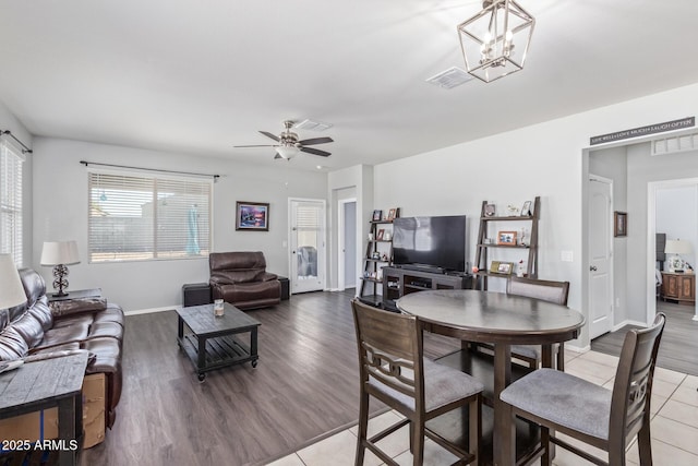 dining room featuring visible vents, light wood-style flooring, baseboards, and ceiling fan with notable chandelier