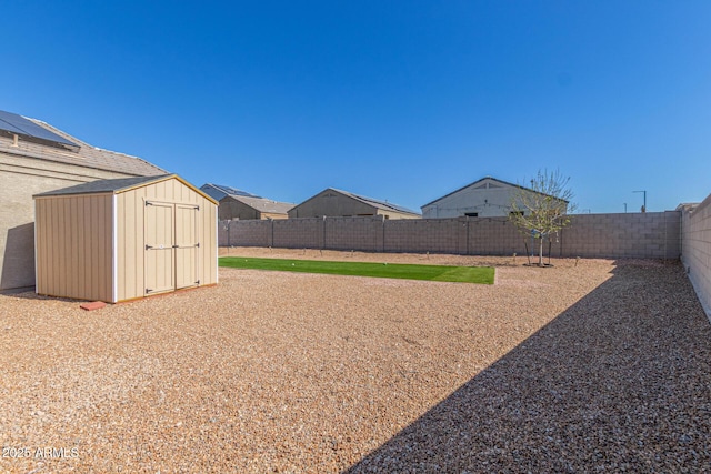 view of yard featuring a fenced backyard, an outdoor structure, and a shed