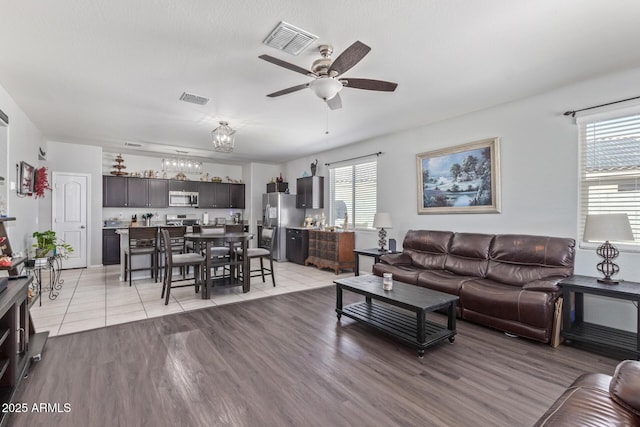 living area featuring plenty of natural light, visible vents, and ceiling fan