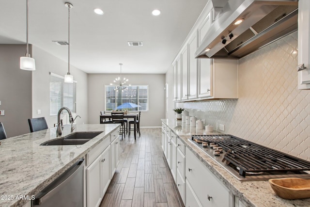 kitchen featuring sink, wall chimney range hood, white cabinets, and appliances with stainless steel finishes