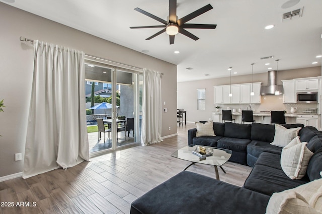 living room featuring ceiling fan, light wood-type flooring, and a wealth of natural light