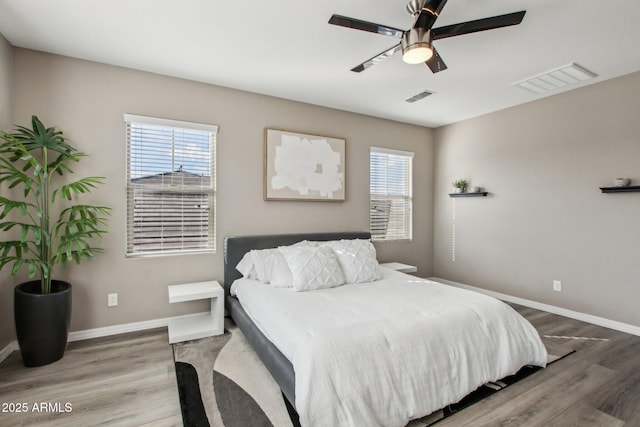 bedroom with ceiling fan, hardwood / wood-style floors, and multiple windows