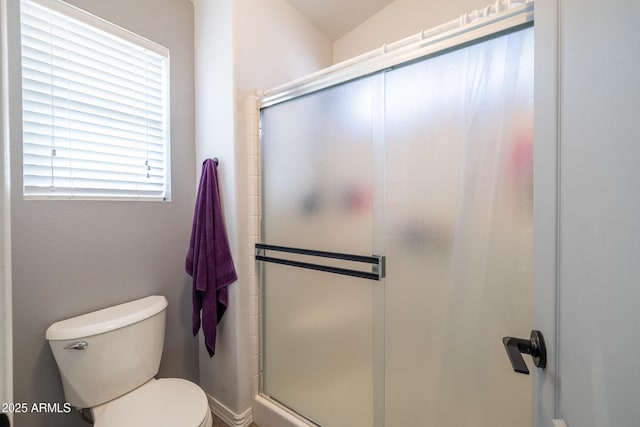 bathroom featuring toilet and a shower with shower door