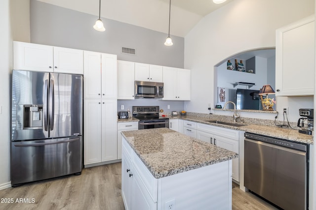 kitchen with decorative light fixtures, stainless steel appliances, a kitchen island, white cabinets, and sink