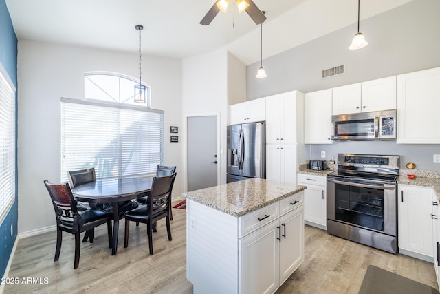 kitchen featuring appliances with stainless steel finishes, white cabinetry, and hanging light fixtures