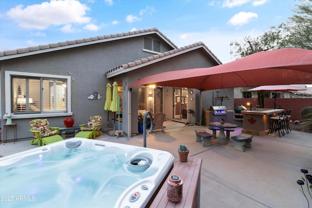 back of house featuring a bar, an outdoor hot tub, and a patio area